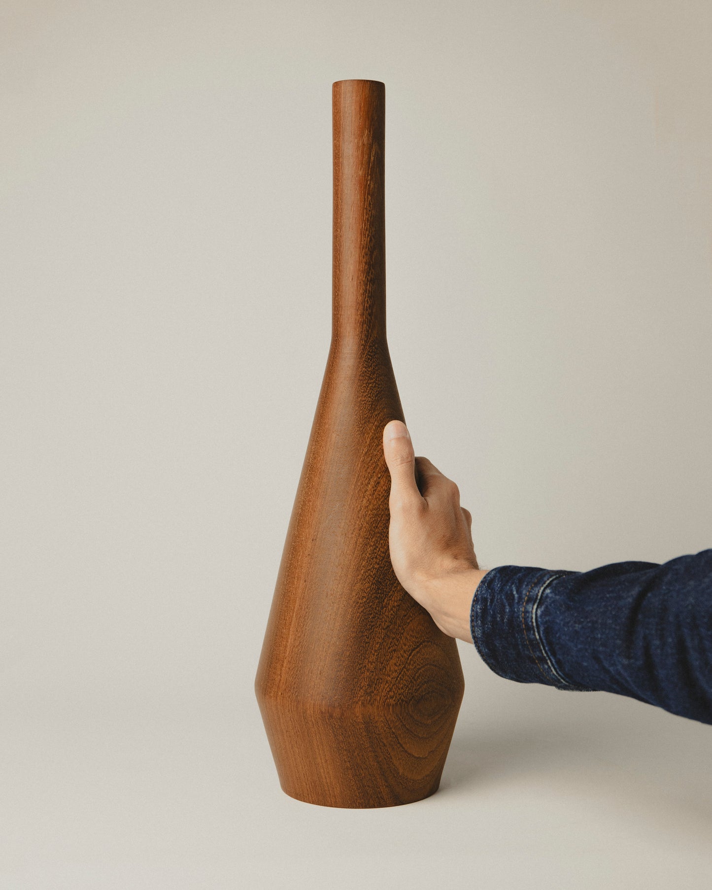 Jarrón de madera iroko modelo 04, con forma cónica sobria. Trabajo artesanal de Yubero Torno. foto con mano