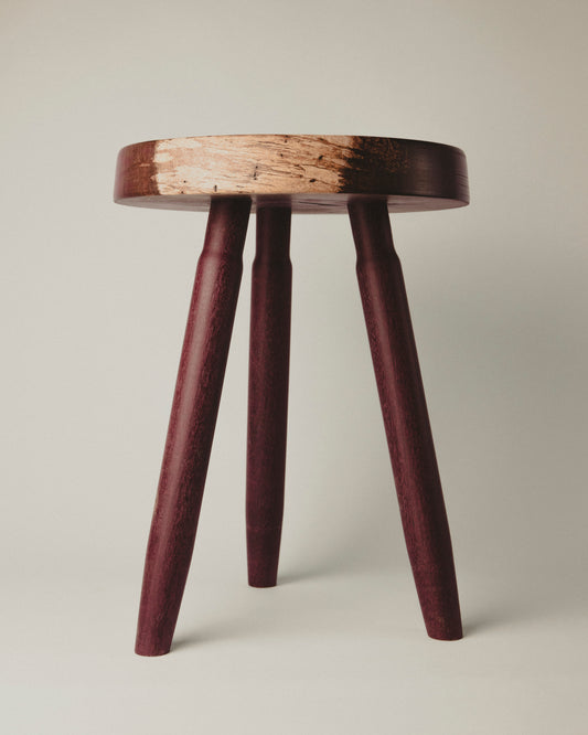 Short stool in purpleheart wood, front view. Made by Yubero Torno.